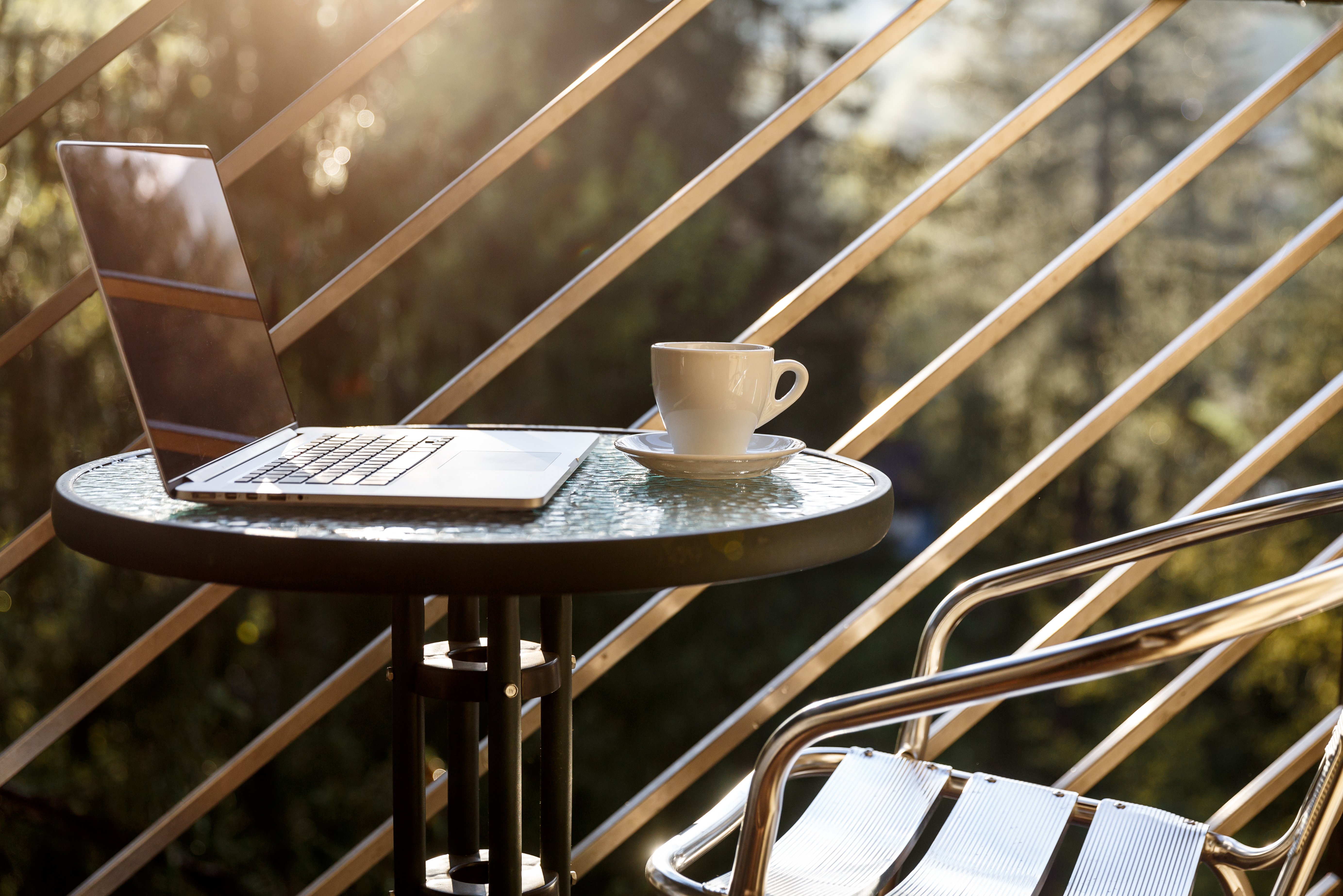 picture of a small table on a balcony with a laptop and coffee mug 