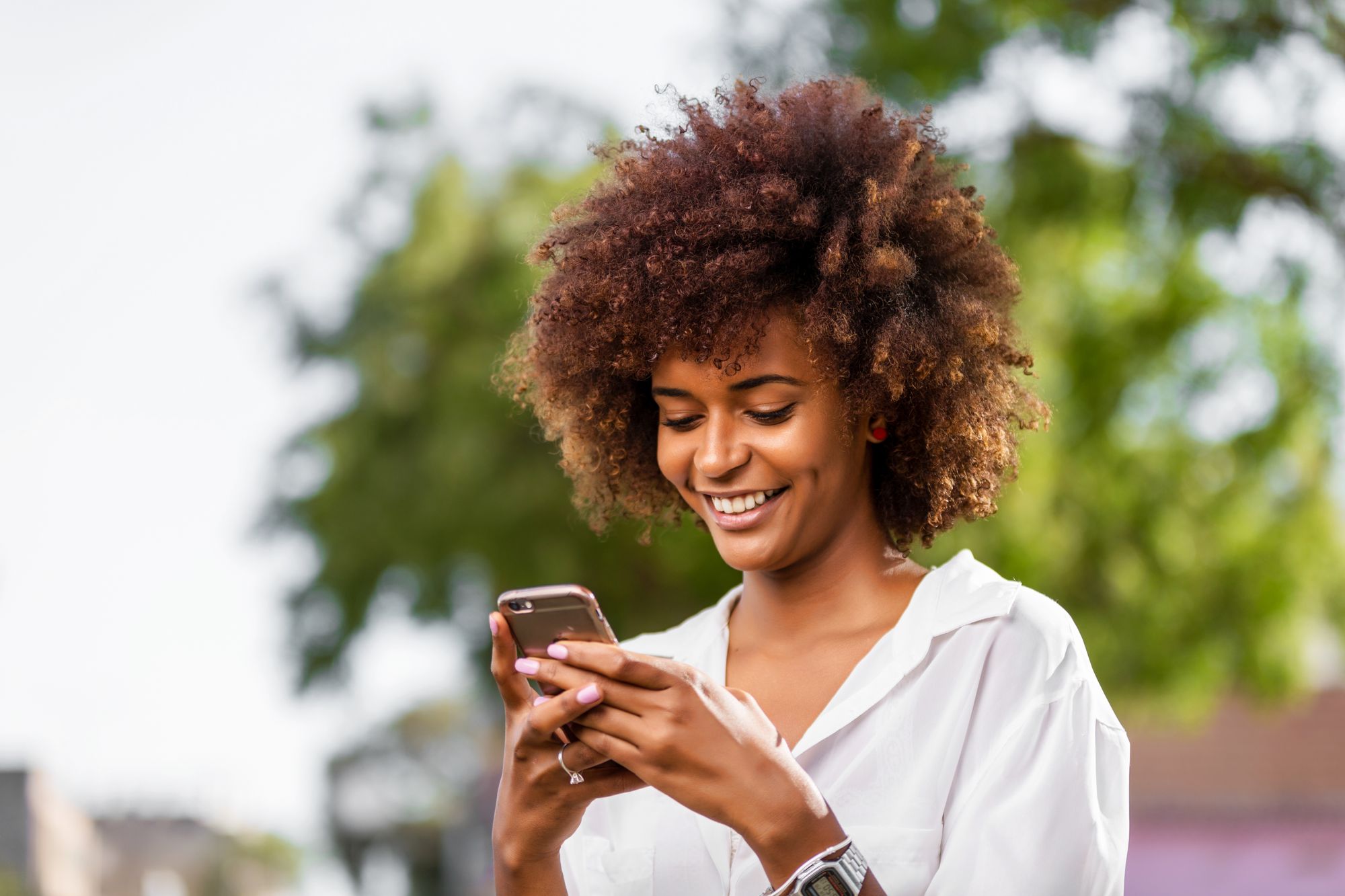 woman with curly dirty blonde hair smiling look at phone