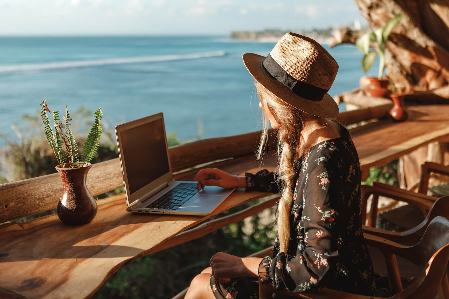 Woman sitting at a counter overlooking the beach using her laptop. 